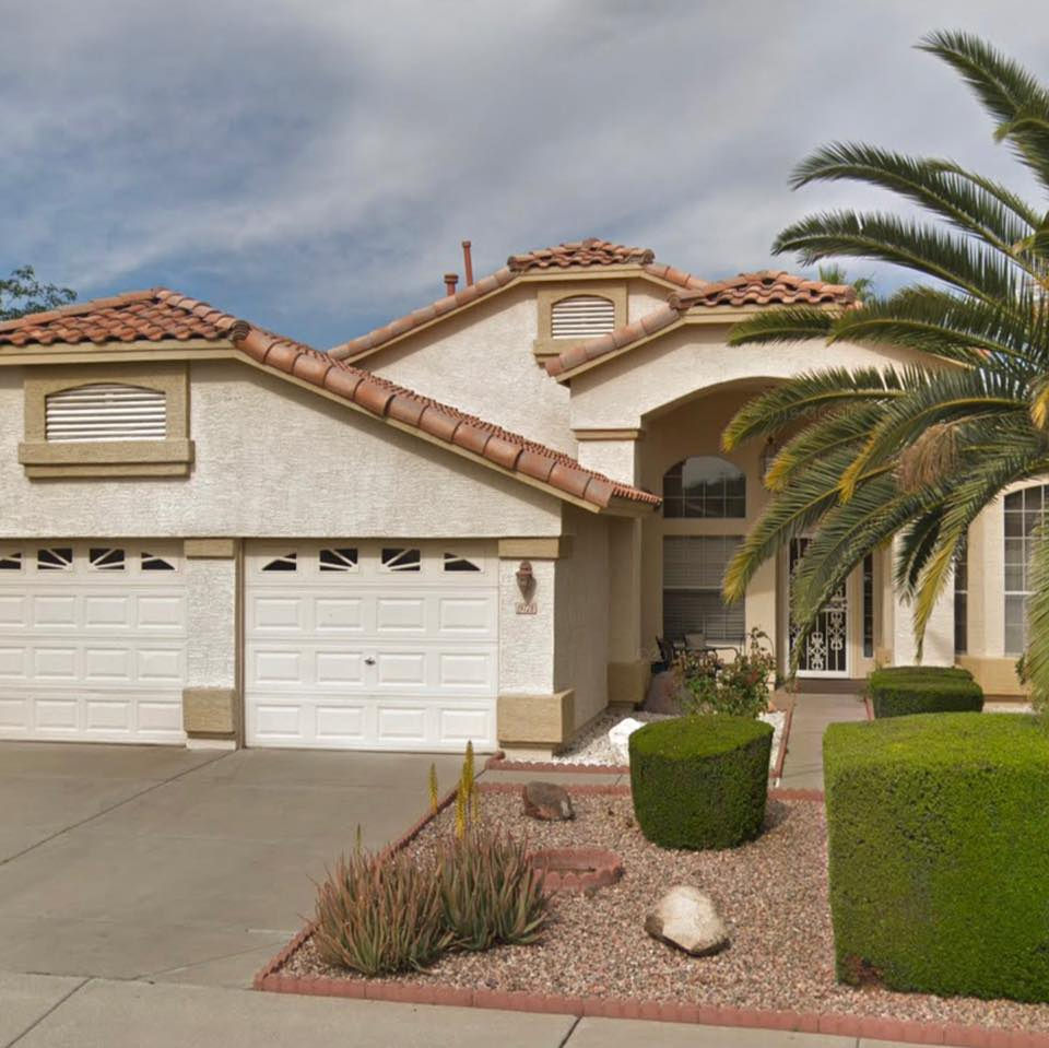 The front of the house: a single-story Arizona home with palm trees and tended gardens