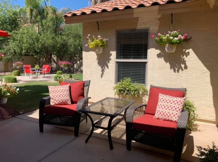 Covered patio with cushioned chairs and pots of flowers