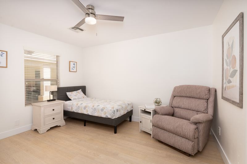 Bedroom with a quilted bed, nightstand and a cushioned recliner