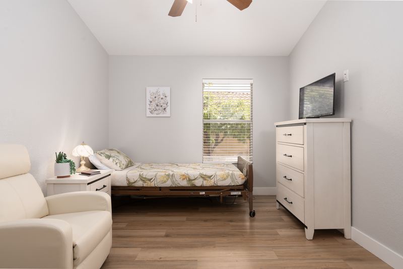 Bedroom with a recliner, dresser, television and a garden window