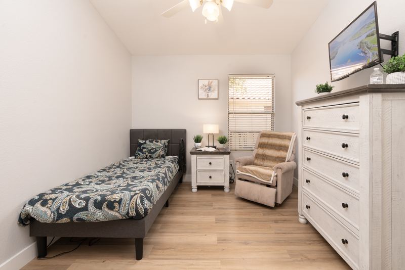 Bedroom with a patterned quilt, recliner and a wide dresser