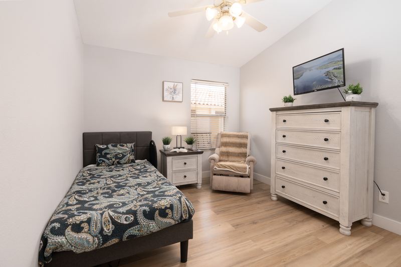 Bedroom with a television above the dresser and a comfortable armchair