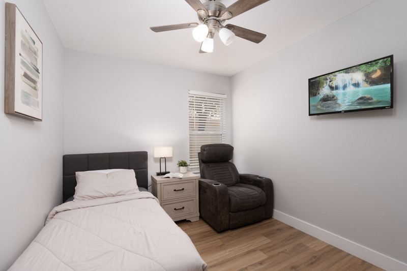 Bedroom with an upholstered headboard, recliner and television