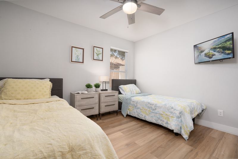 Shared bedroom with two beds, nightstands and framed artwork