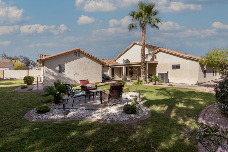 Backyard lawn, palm trees and a shaded patio dining set
