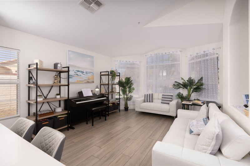 Living room with a piano, bookshelves and white sofas
