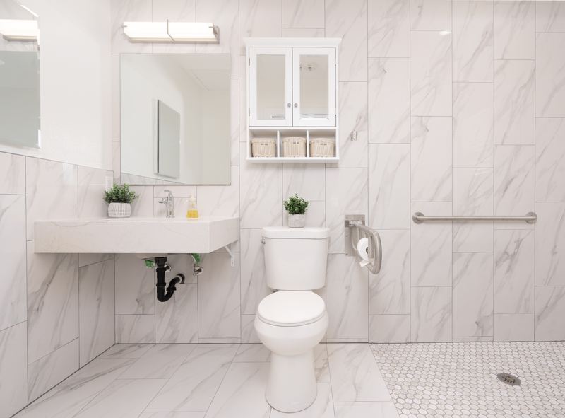Accessible bathroom in marble tile with grab bars and a wall-mounted sink