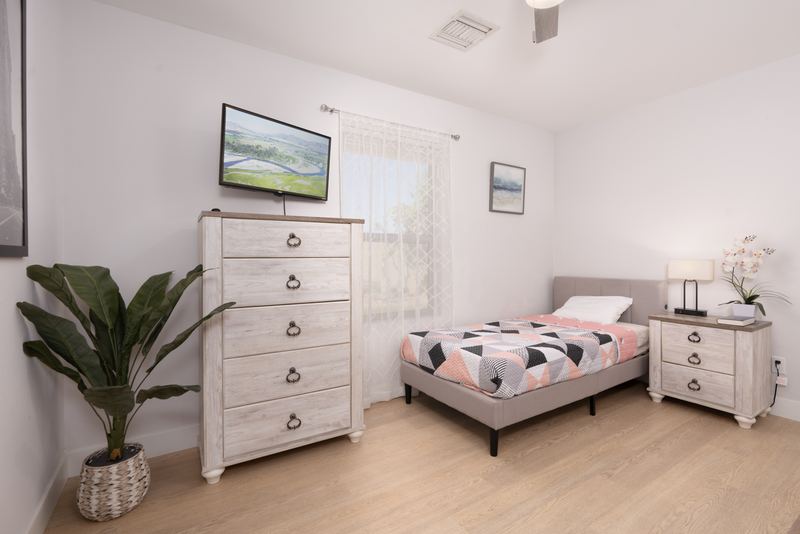Bedroom with a dresser, bedside lamps and a wall-mounted television